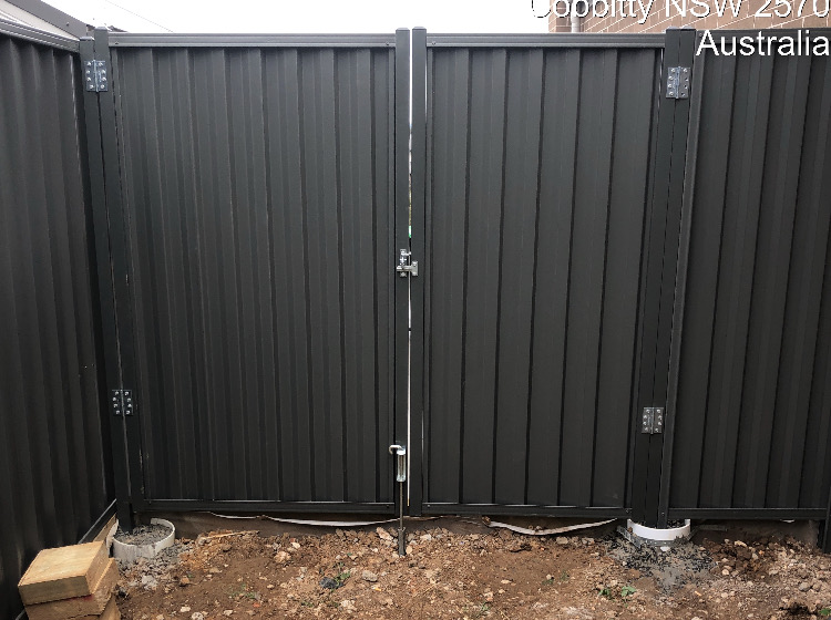 Heavy-duty Colorbond double swing gate in matte charcoal between matching fence panels.