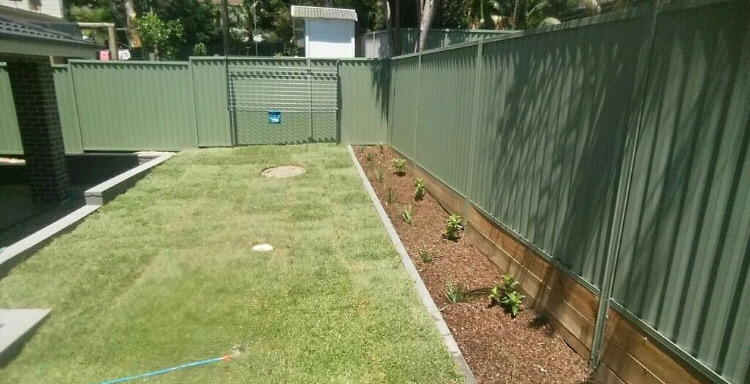 Established back lawn with timber sleeper retaining edge and a thin mulched garden bed.
